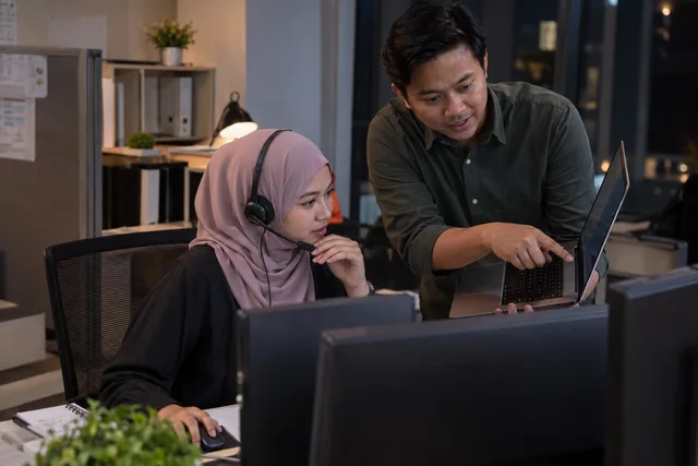 An IT specialist investigates a reported laptop issue with a colleague.